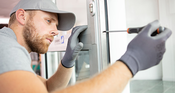 a man wearing a grey hat using a screwdriver to install a uPVC door lock
