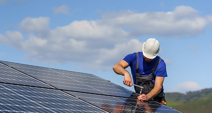 a man with a white helmet using a spanner to install solar panels onto a roof