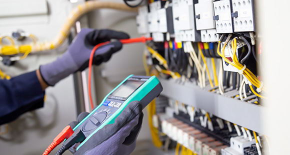 an technician testing electrical safety compliance on a fuse board