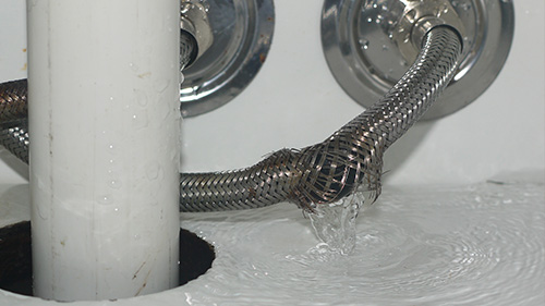 a broken pipe leaking water in a bathroom cupboard