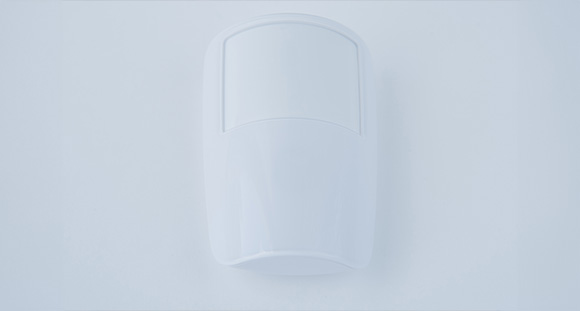 a white PIR security sensor on a white wall